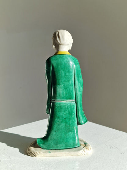 A Chinese sancai-glazed biscuit figure of a Luohan holding a ruyi — Kangxi period (1662–1722)