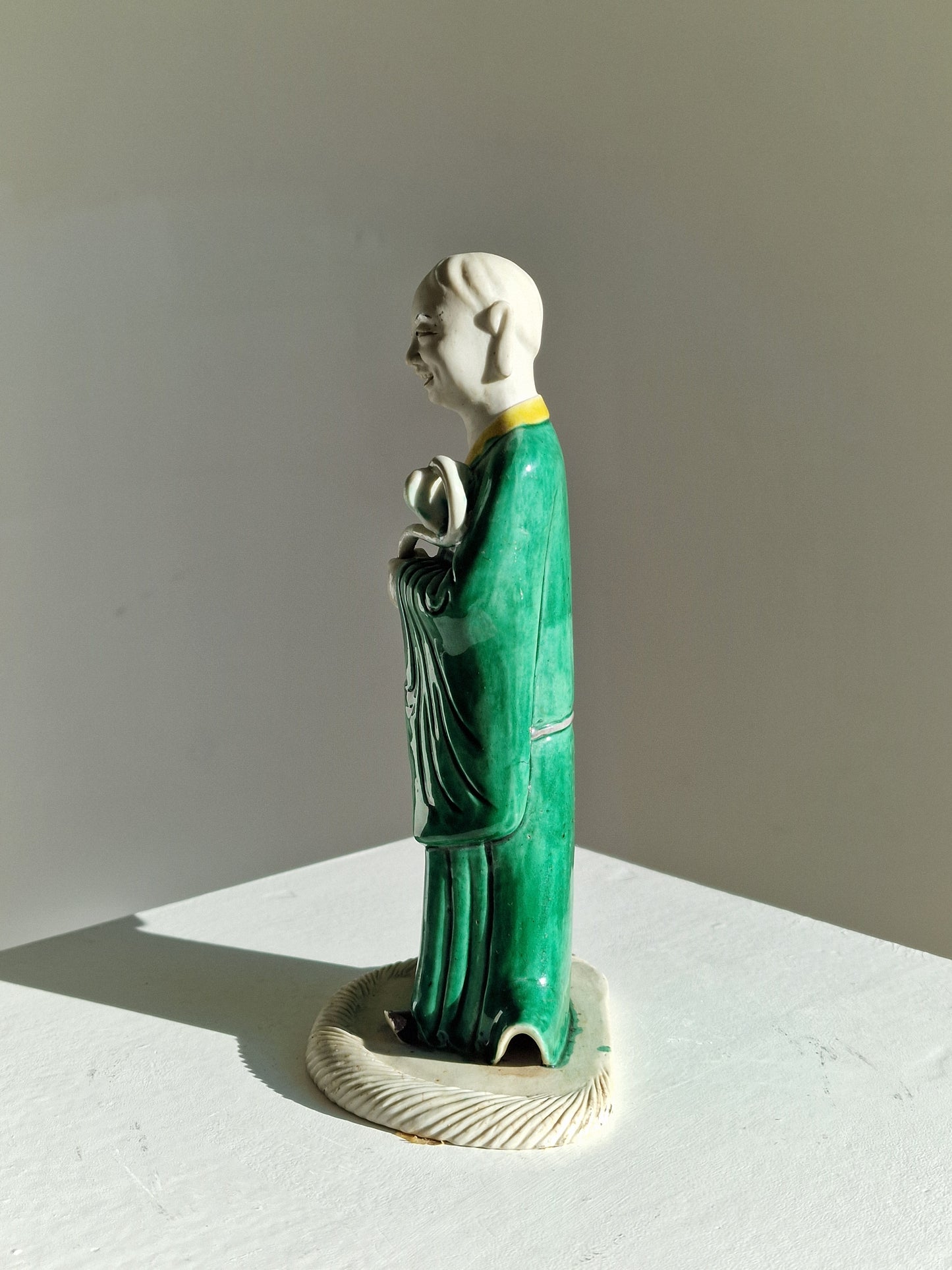 A Chinese sancai-glazed biscuit figure of a Luohan holding a ruyi — Kangxi period (1662–1722)