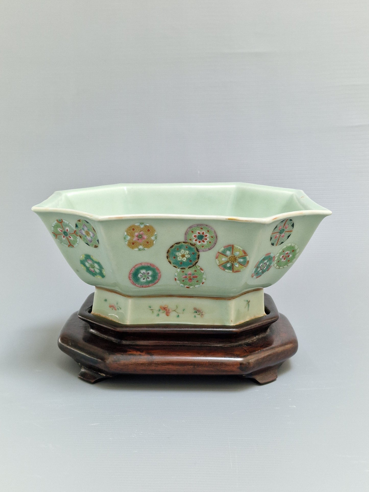 A Chinese octagonal famille rose celadon-ground 'Brocade Balls' offering bowl on a wooden stand, bearing a Daoguang mark, 19th century