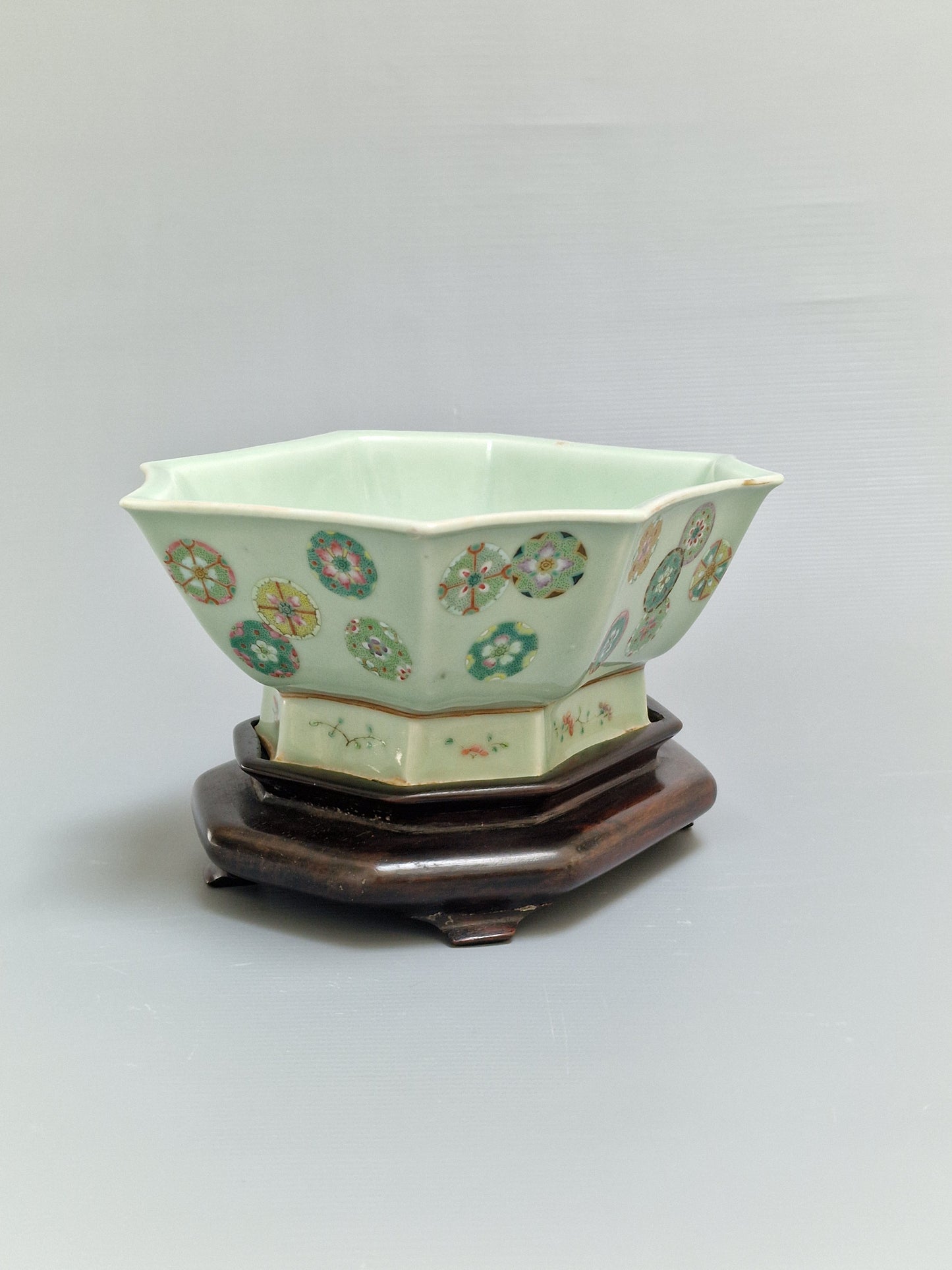 A Chinese octagonal famille rose celadon-ground 'Brocade Balls' offering bowl on a wooden stand, bearing a Daoguang mark, 19th century