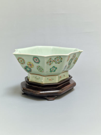 A Chinese octagonal famille rose celadon-ground 'Brocade Balls' offering bowl on a wooden stand, bearing a Daoguang mark, 19th century