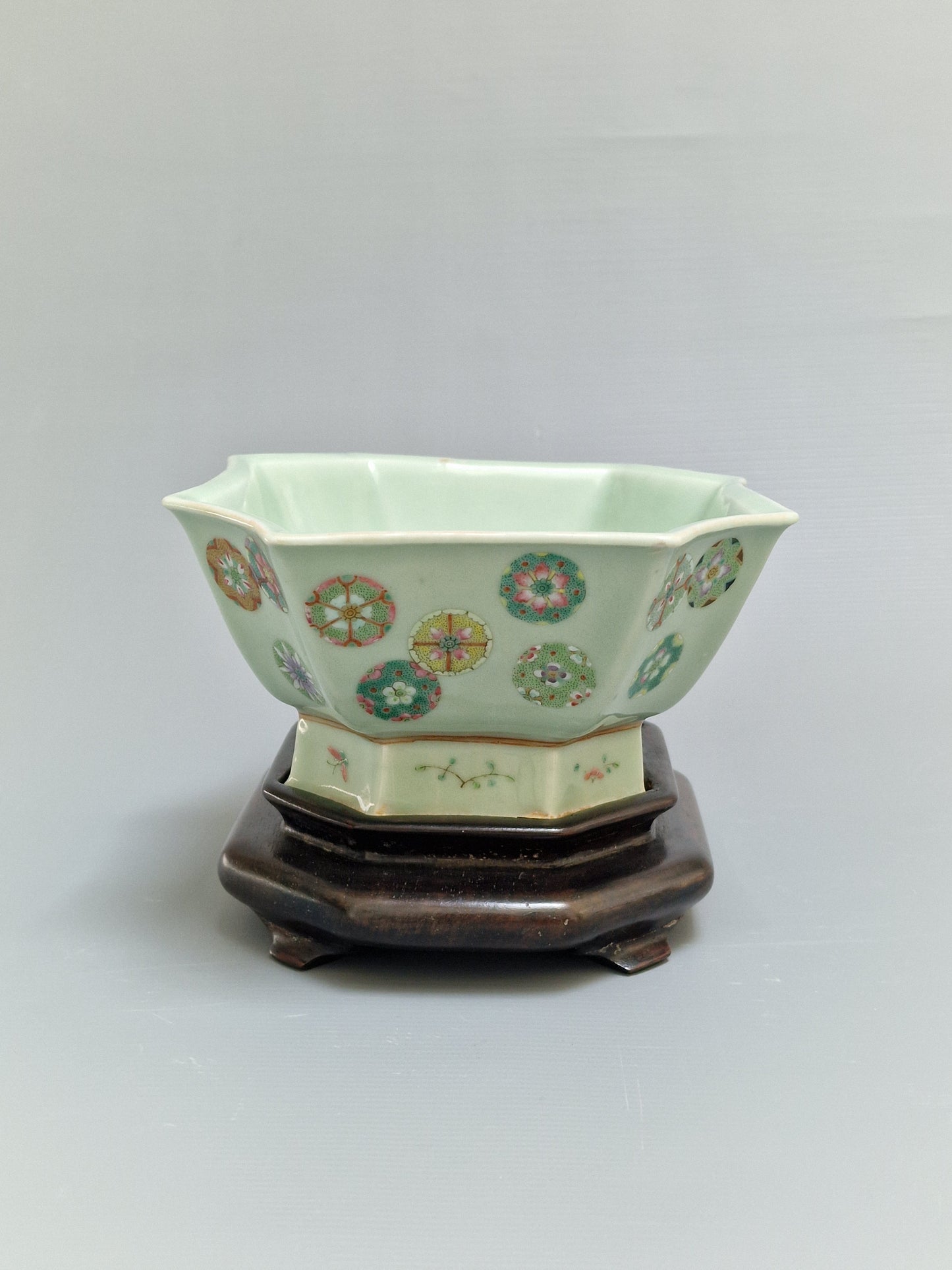 A Chinese octagonal famille rose celadon-ground 'Brocade Balls' offering bowl on a wooden stand, bearing a Daoguang mark, 19th century