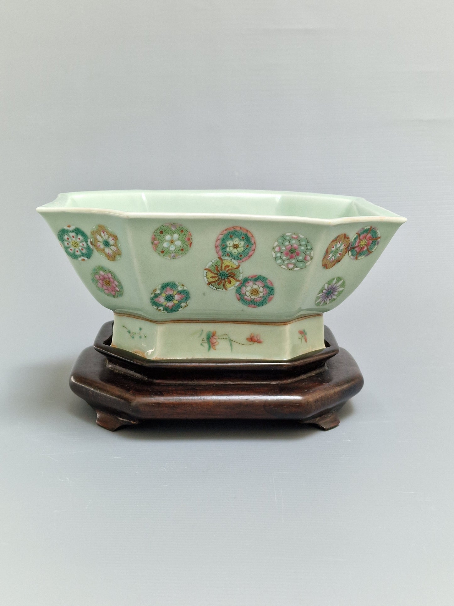 A Chinese octagonal famille rose celadon-ground 'Brocade Balls' offering bowl on a wooden stand, bearing a Daoguang mark, 19th century