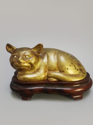 A Chinese bronze gilded cat with pearl eyes on a wooden base, Early 20th century