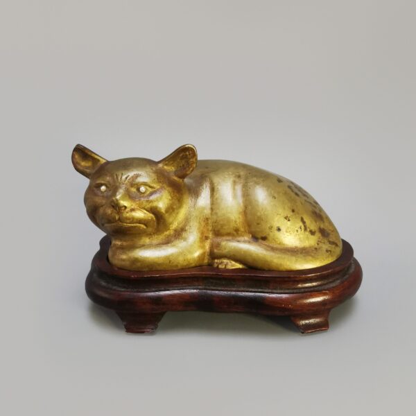 A Chinese bronze gilded cat with pearl eyes on a wooden base, Early 20th century