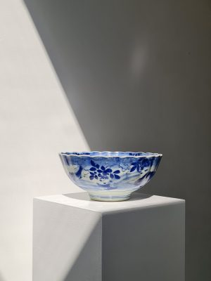 A Japanese blue-white pleated porcelain bowl with a decor of carp and a botanical decor in the middle, 18th century